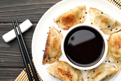 Photo of Delicious fried gyoza dumplings with sesame seeds served on wooden table, top view