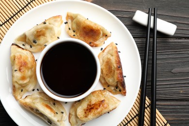 Photo of Delicious fried gyoza dumplings with sesame seeds served on wooden table, top view