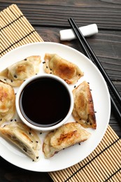 Photo of Delicious fried gyoza dumplings with sesame seeds served on wooden table, top view