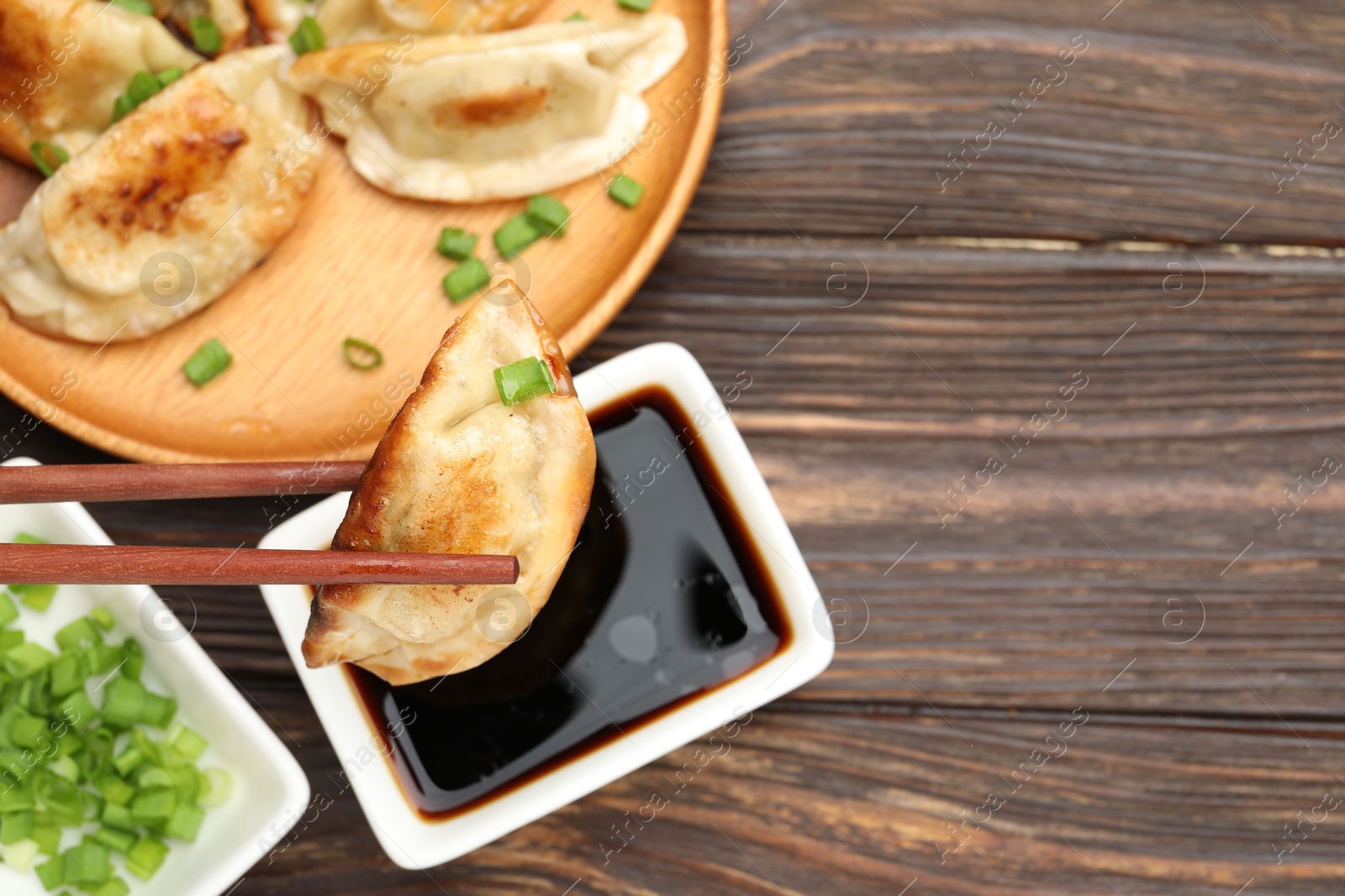 Photo of Eating fried gyoza dumplings at wooden table, top view. Space for text