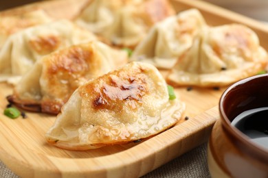 Photo of Delicious fried gyoza dumplings with green onions and soy sauce on table, closeup