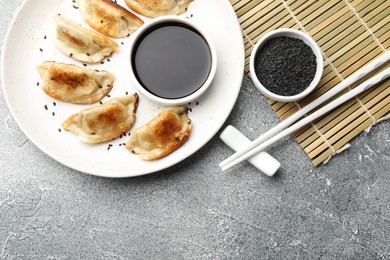 Photo of Delicious fried gyoza dumplings with sesame seeds served on grey table, flat lay. Space for text