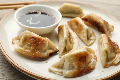 Photo of Fried gyoza dumplings with soy sauce on wooden table, closeup