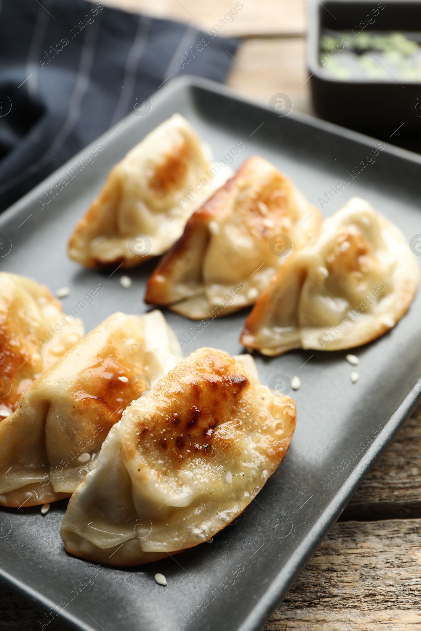 Photo of Fried gyoza dumplings with sesame seeds on wooden table, closeup