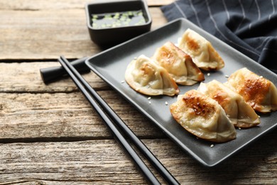 Photo of Delicious fried gyoza dumplings with sesame seeds served on wooden table