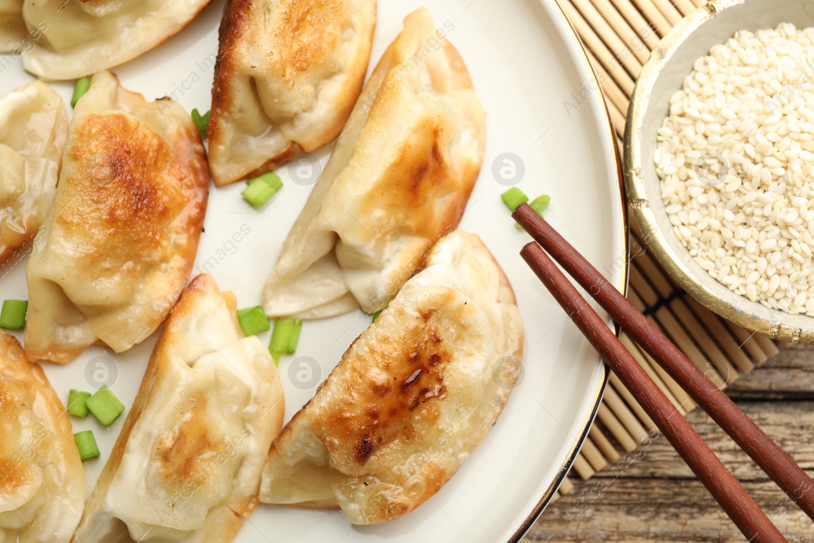 Photo of Delicious fried gyoza dumplings with green onions served on table, closeup