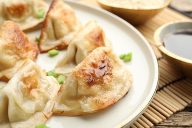 Photo of Delicious fried gyoza dumplings with green onions served on table, closeup