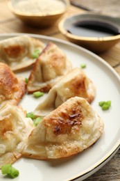 Photo of Delicious fried gyoza dumplings with green onions served on table, closeup