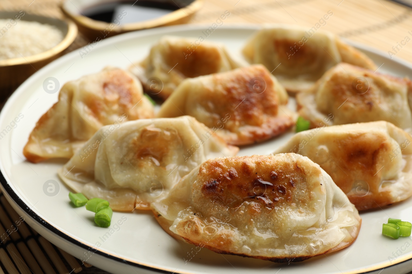 Photo of Delicious fried gyoza dumplings with green onions served on table, closeup