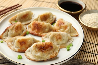 Photo of Delicious fried gyoza dumplings with green onions served on table, closeup