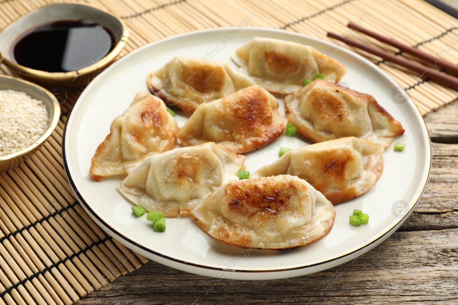 Photo of Delicious fried gyoza dumplings with green onions served on table, closeup