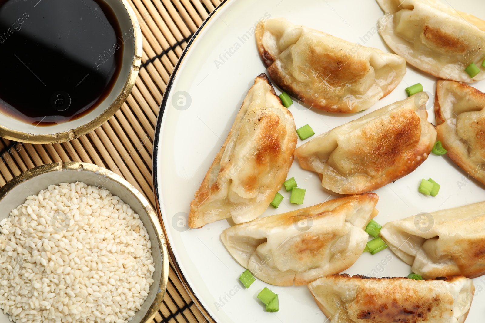 Photo of Delicious fried gyoza dumplings with green onions served on table, flat lay