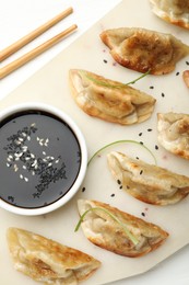 Photo of Delicious fried gyoza dumplings with sesame seeds served on white table, top view