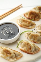 Photo of Delicious fried gyoza dumplings with sesame seeds served on white table, closeup