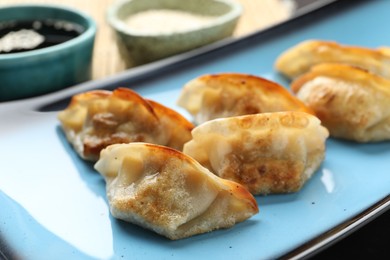 Photo of Fried gyoza dumplings and soy sauce on table, closeup