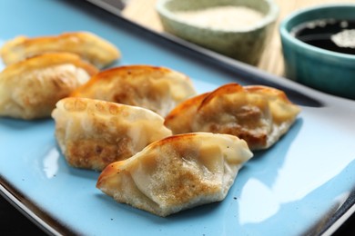 Photo of Fried gyoza dumplings and soy sauce on table, closeup