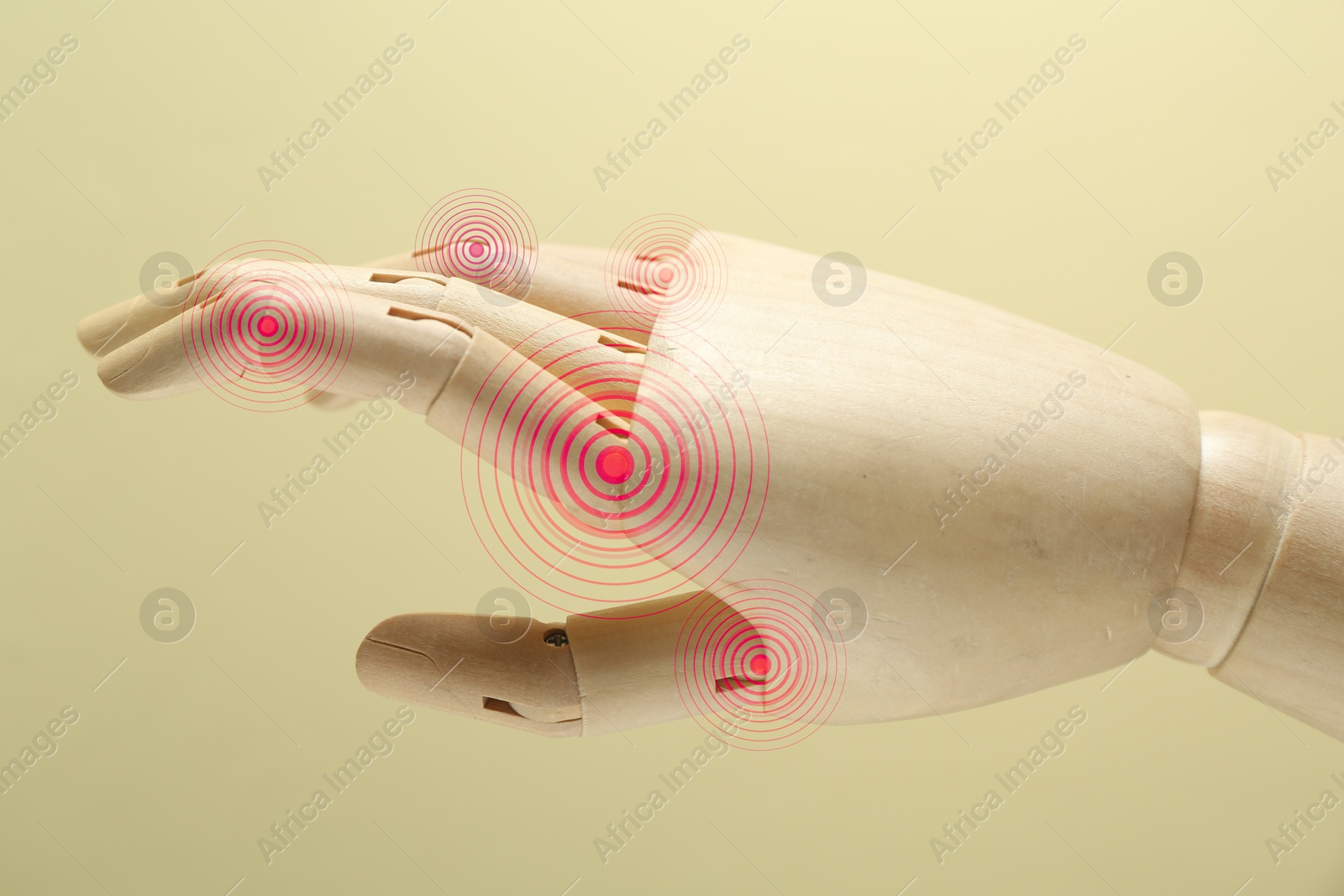 Image of Joint inflammation. Wooden mannequin hand with highlighted areas on fingers against beige background, closeup