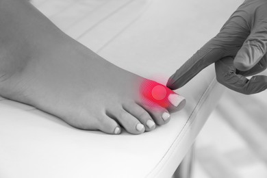 Image of Joint inflammation. Doctor checking woman's foot at hospital, closeup. Toned in black-and-white with color area on toe