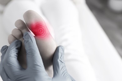 Image of Joint inflammation. Doctor checking woman's foot at hospital, closeup. Toned in black-and-white with color area on toe