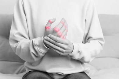 Image of Woman with joint inflammation indoors, closeup. Toned in black-and-white with color areas on fingers