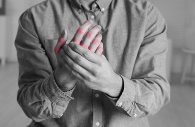 Image of Man with joint inflammation indoors, closeup. Toned in black-and-white with color areas on fingers