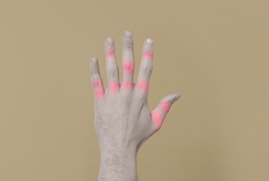 Image of Man with joint inflammation on grey background, closeup. Toned in black-and-white with color areas on fingers