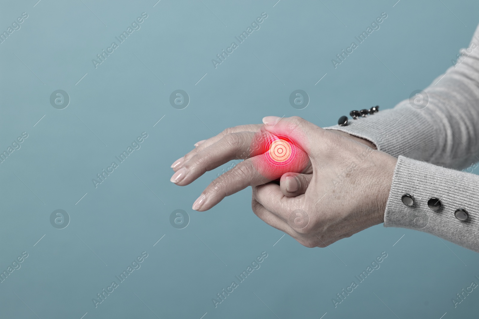 Image of Woman with joint inflammation on pale blue background, closeup. Red area on finger