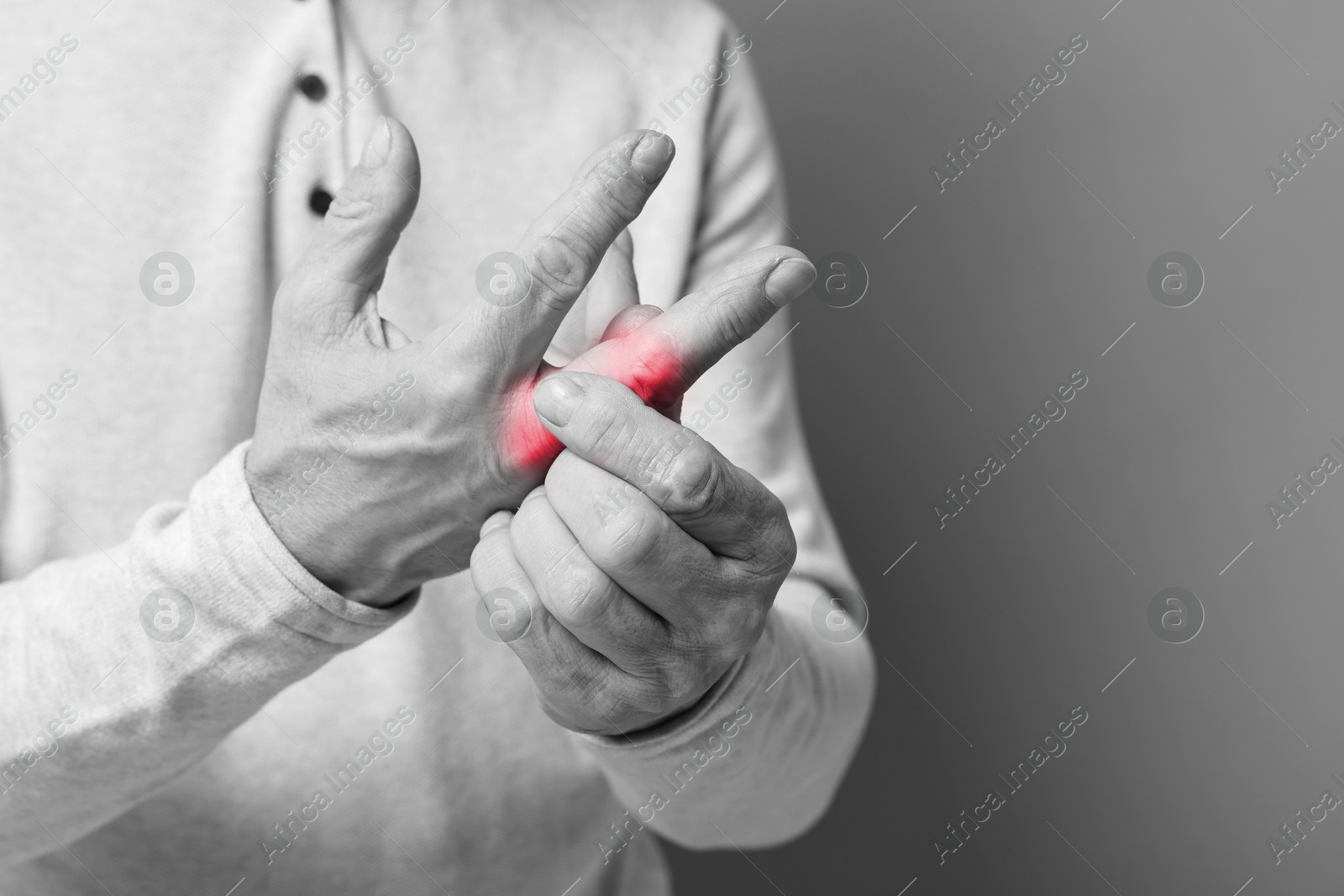 Image of Man with joint inflammation on grey background, closeup. Toned in black-and-white with color areas on fingers