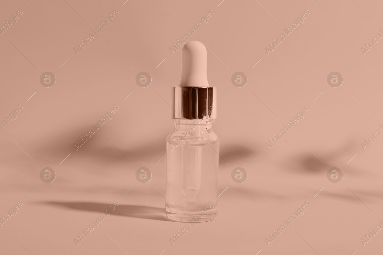 Image of Bottle of serum on color background, toned in mocha mousse shade. Color of 2025 year