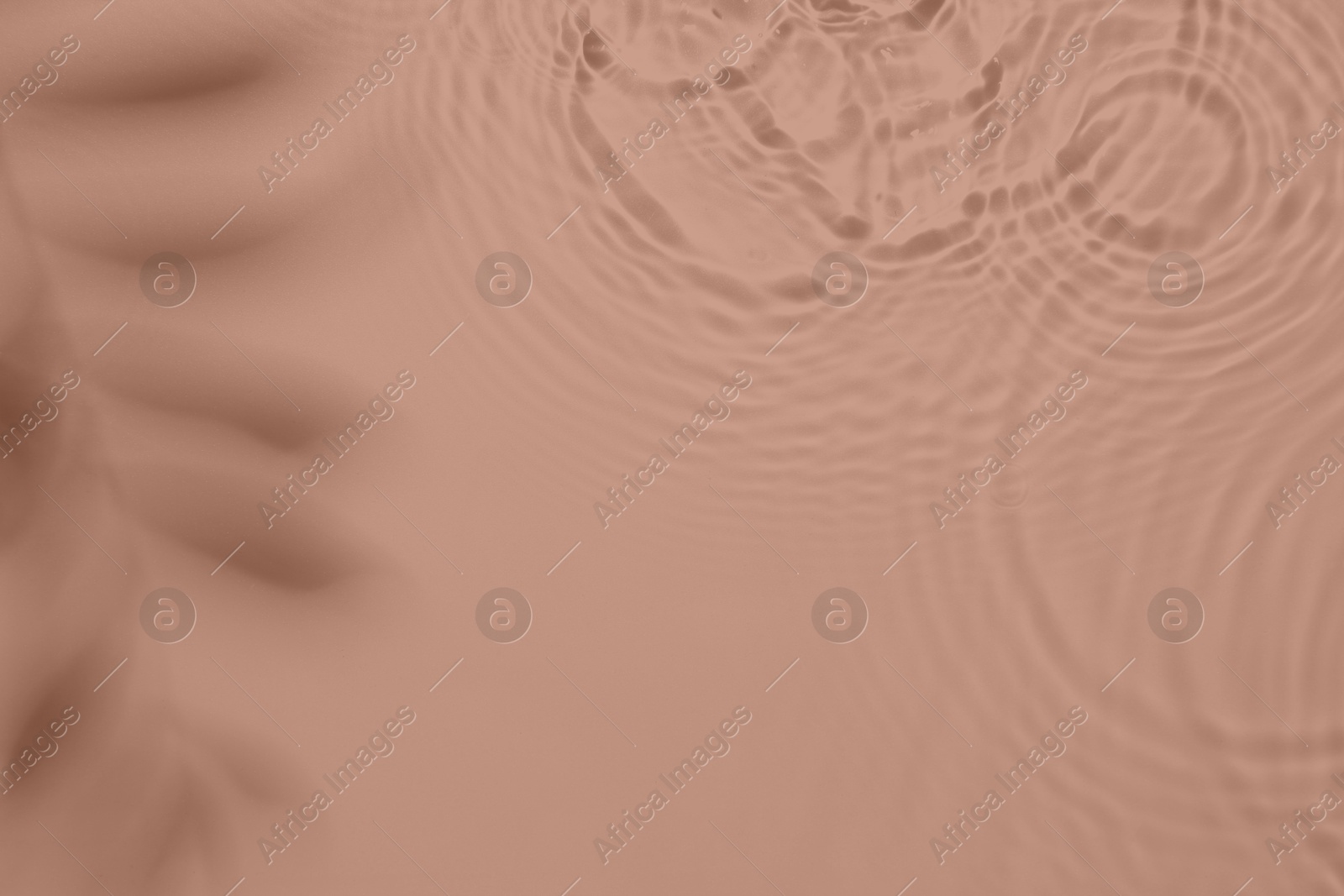 Image of Rippled surface of water on mocha mousse background, top view. Color of 2025 year