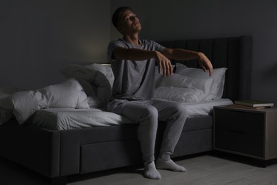 Photo of Young man suffering from sleepwalking on bed at home