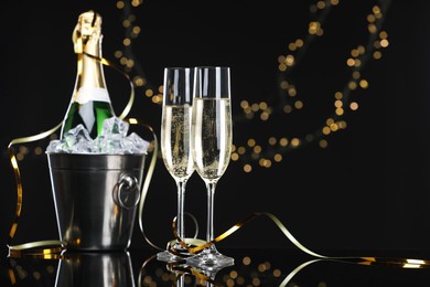 Photo of Champagne and bucket of ice on mirror surface against black background with blurred lights, space for text