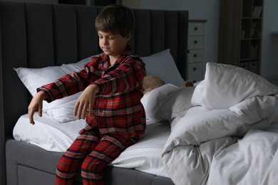 Little boy suffering from sleepwalking on bed at home