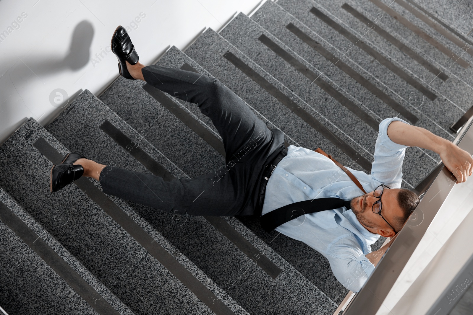 Photo of Injured man on stairs in building after fall, above view. Dangerous accident