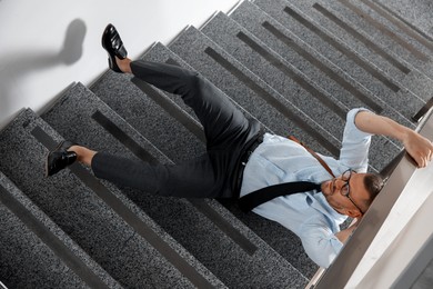 Photo of Injured man on stairs in building after fall, above view. Dangerous accident