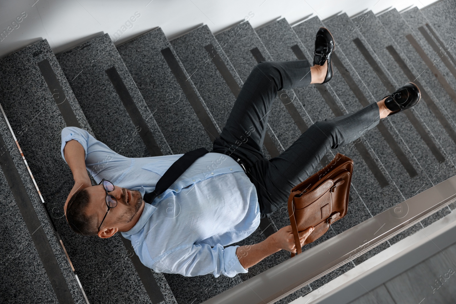 Photo of Man with injured head on stairs in building after fall, above view. Dangerous accident