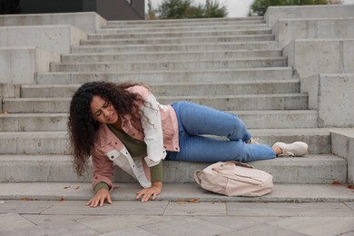 Photo of Injured woman on stairs outdoors after fall. Dangerous accident