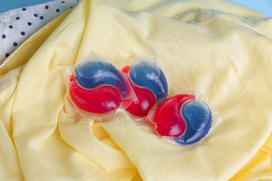 Photo of Laundry detergent capsules on clean clothes, closeup