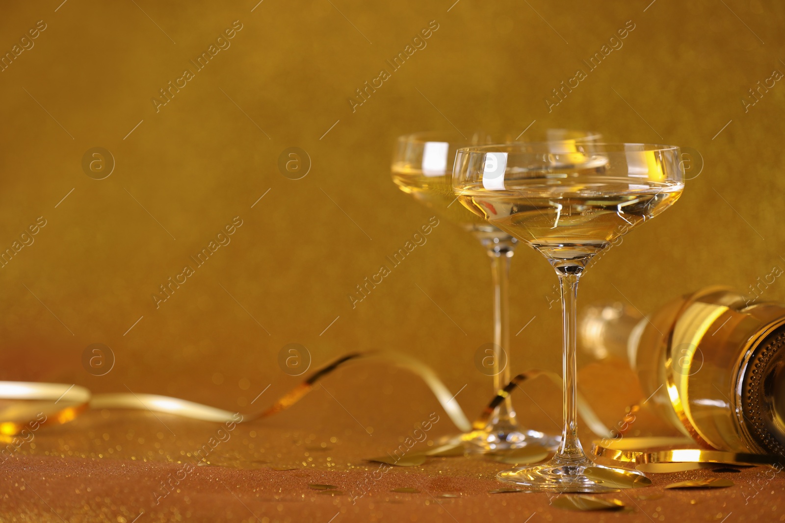 Photo of Champagne, confetti and streamers on golden background. Space for text