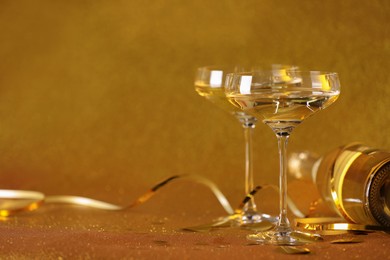 Photo of Champagne, confetti and streamers on golden background. Space for text