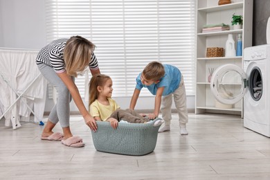 Happy housewife and her kids playing together in laundry room