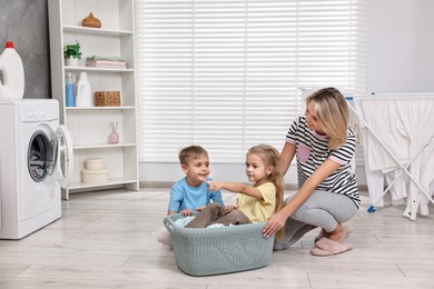 Photo of Happy housewife and her kids playing together in laundry room