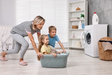 Photo of Happy housewife and her kids playing together in laundry room