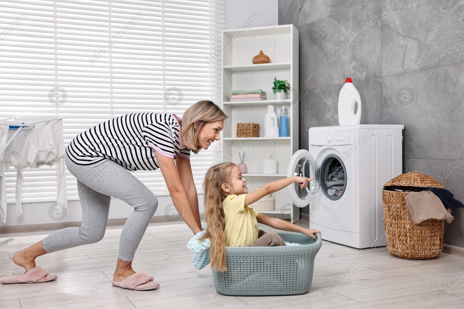 Photo of Happy housewife and her daughter playing together in laundry room