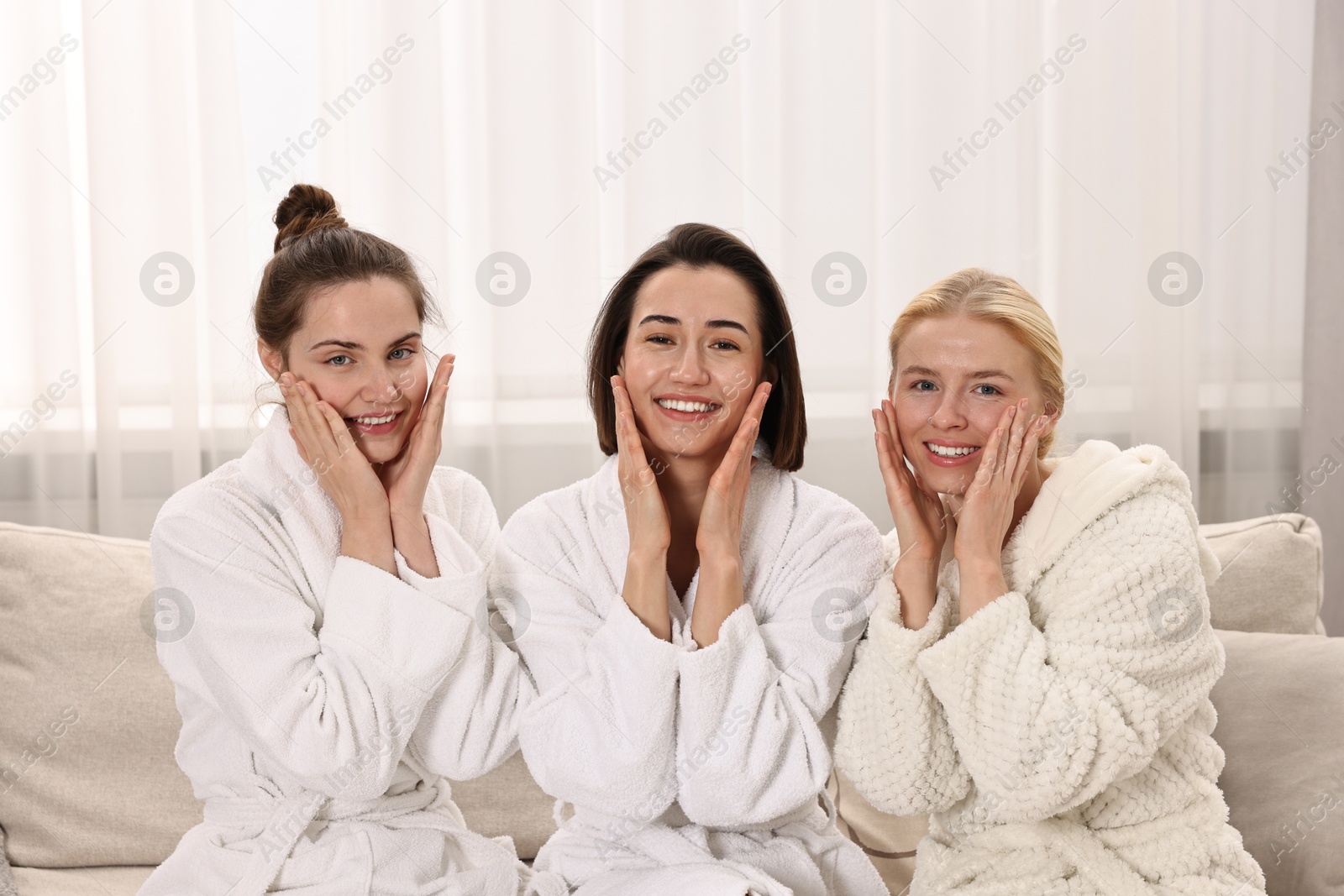 Photo of Happy woman wearing bathrobes on sofa in spa