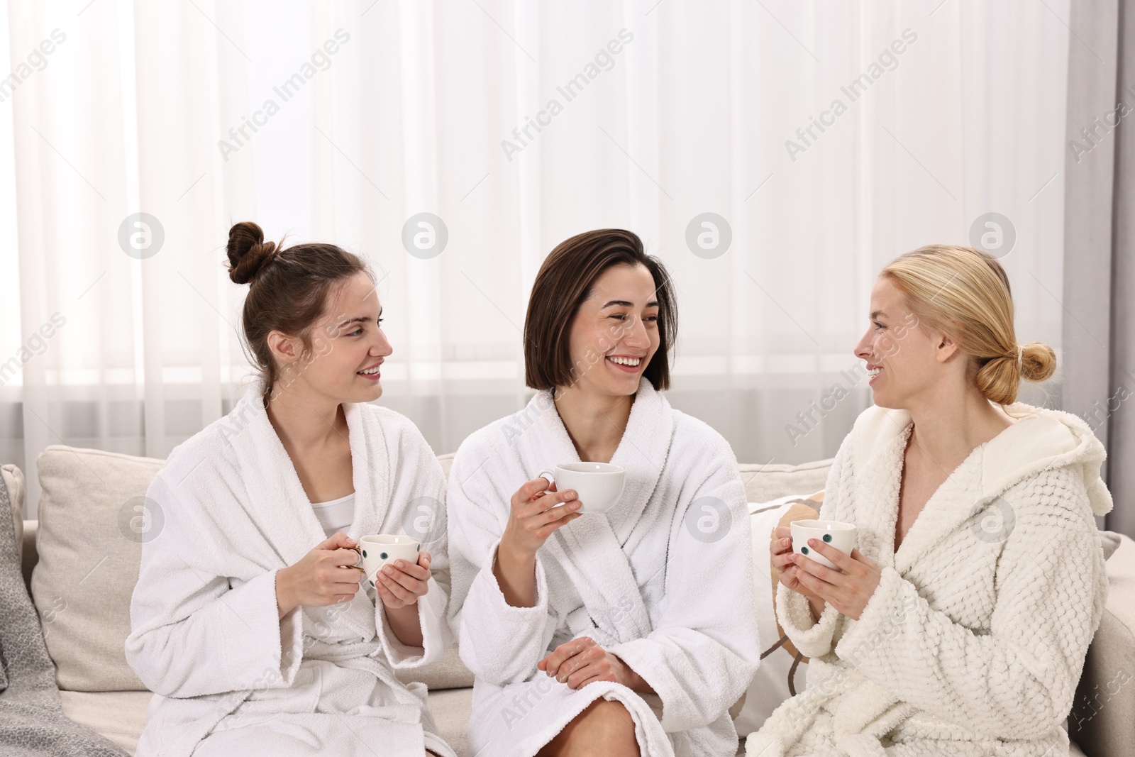 Photo of Beautiful women having tea on sofa in spa