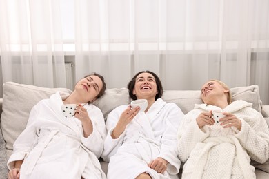 Photo of Beautiful women with tea resting on sofa in spa