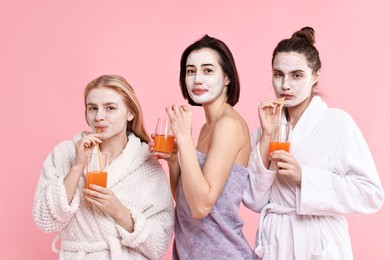 Photo of Spa day. Beautiful women with face masks and healthy drinks on pink background