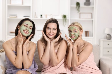 Photo of Spa day. Beautiful women with face masks on sofa indoors