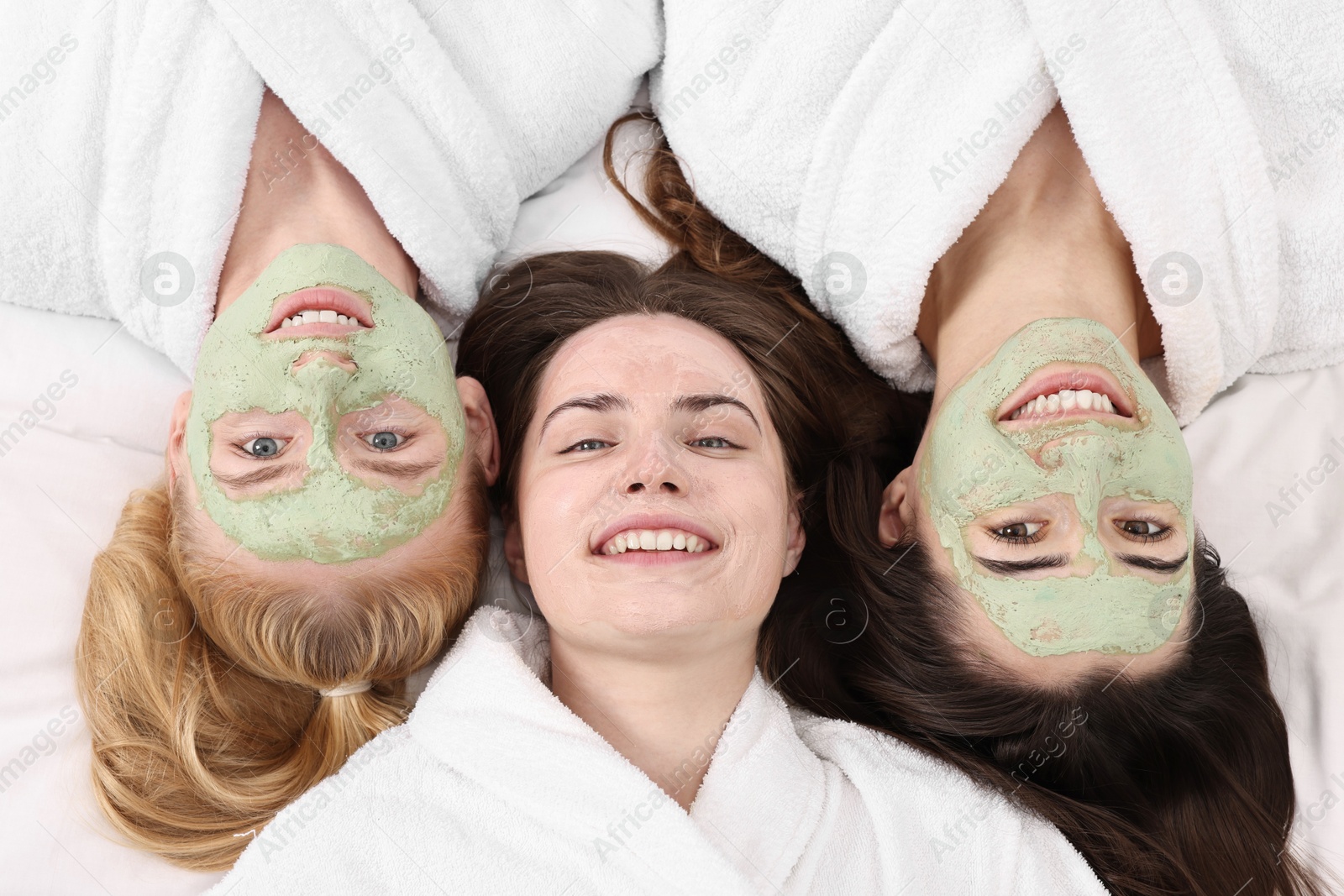 Photo of Spa day. Beautiful woman with face masks on bed, above view